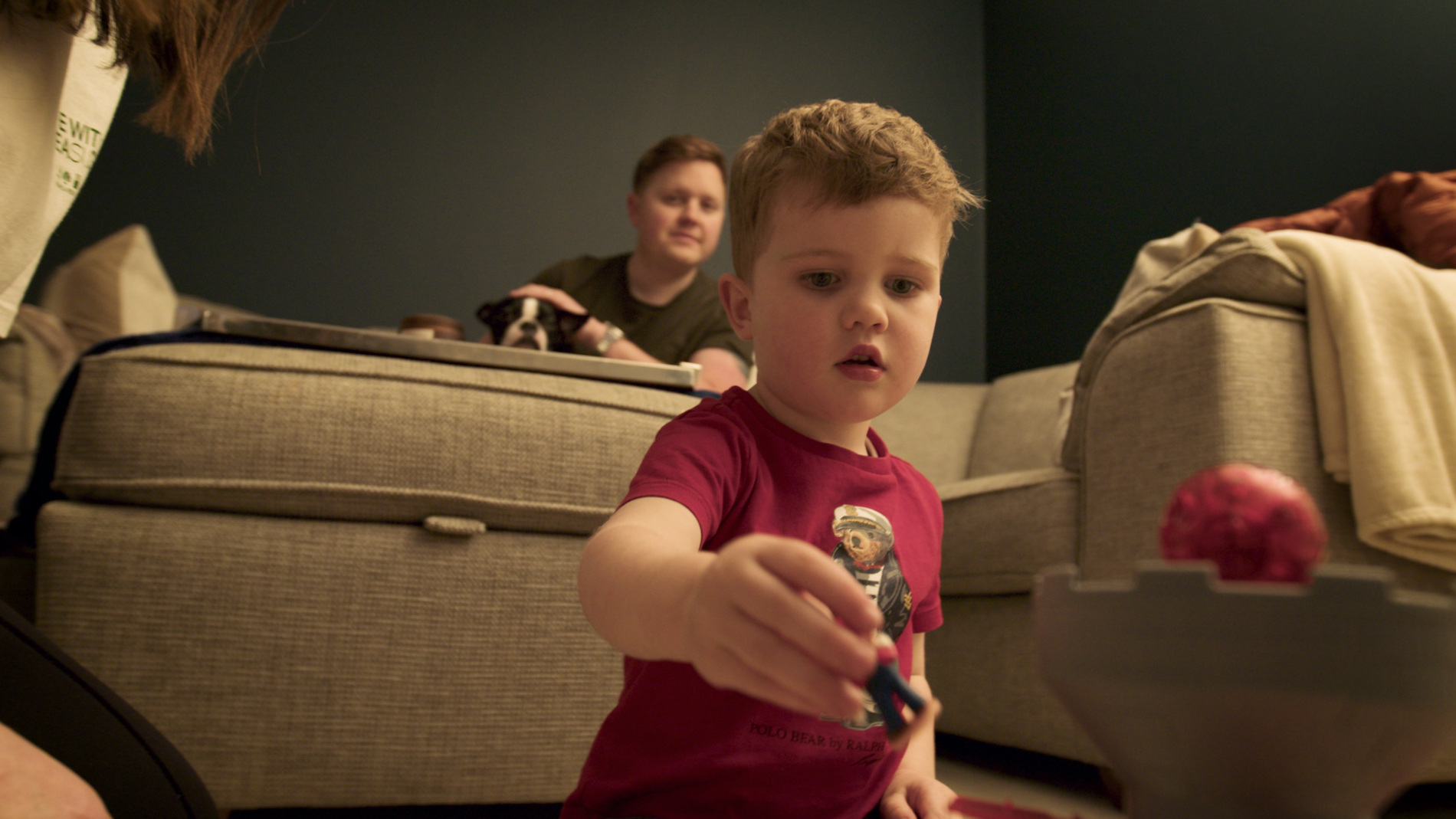 Little boy playing with toys next to couch.