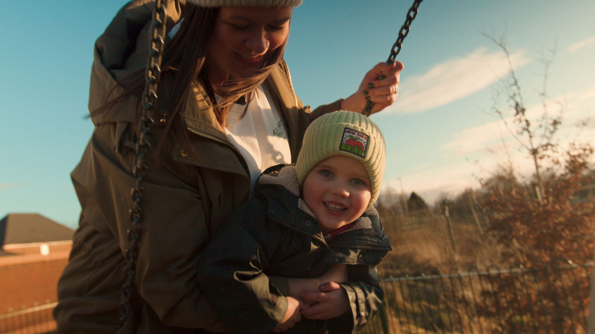 Mother pushing son on swing.