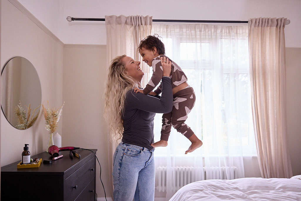 Mother catching child jumping off bed.