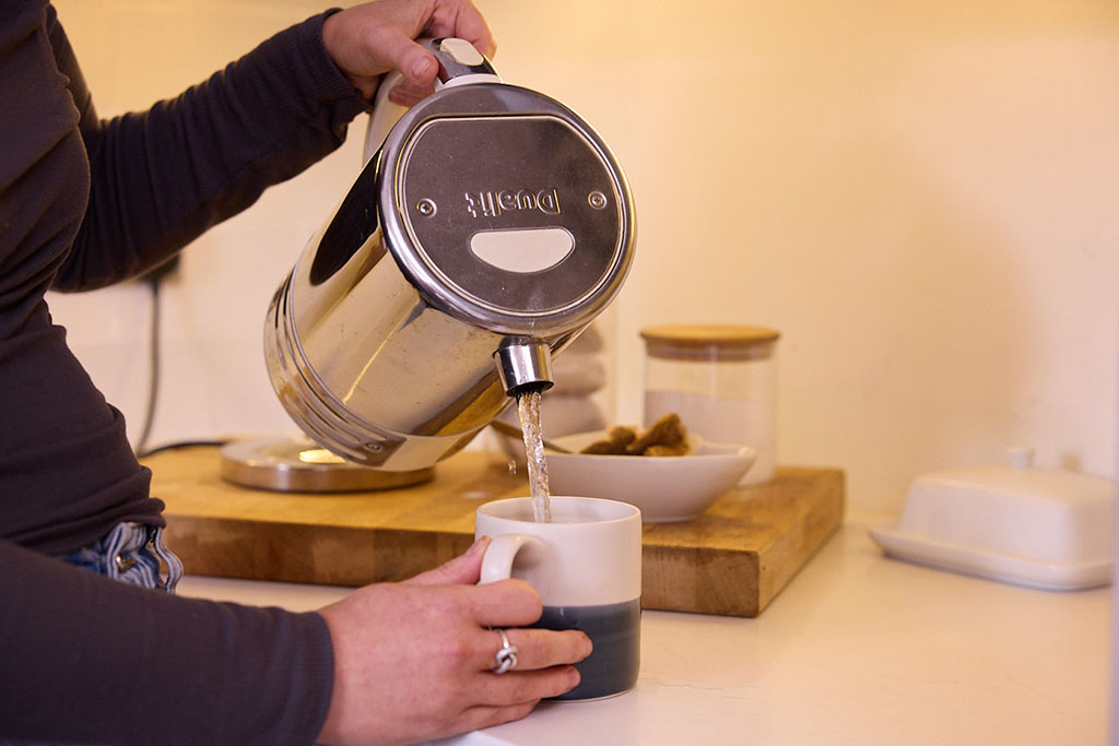 Pouring water from kettle into a mug.