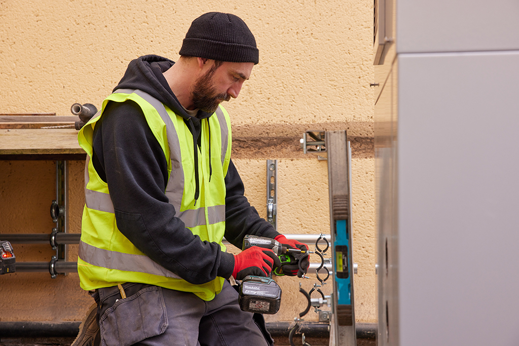 Installer with tools working on a heat pump.
