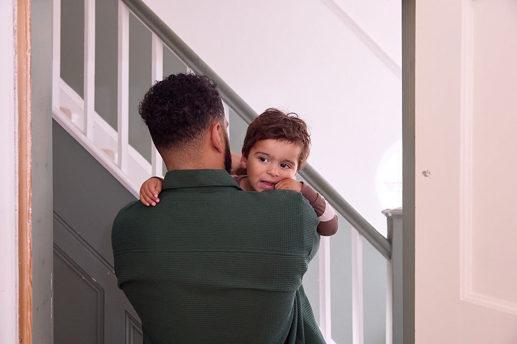 Father carrying son to bed.