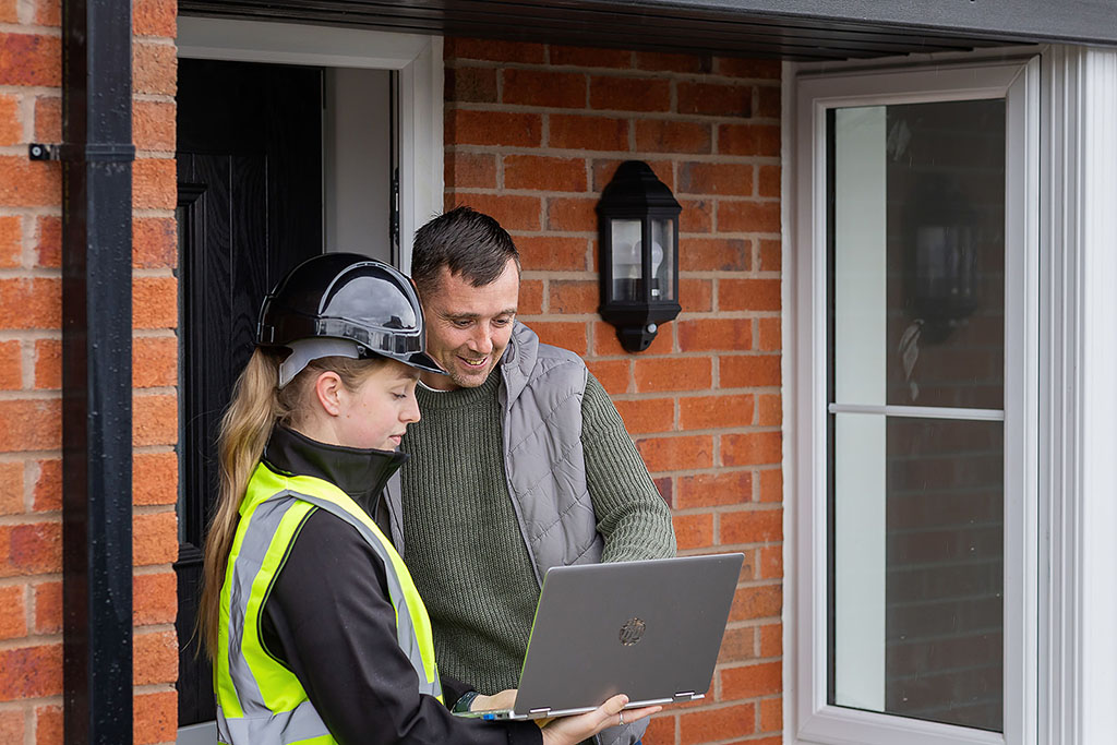 Installer and homeowner looking at laptop.