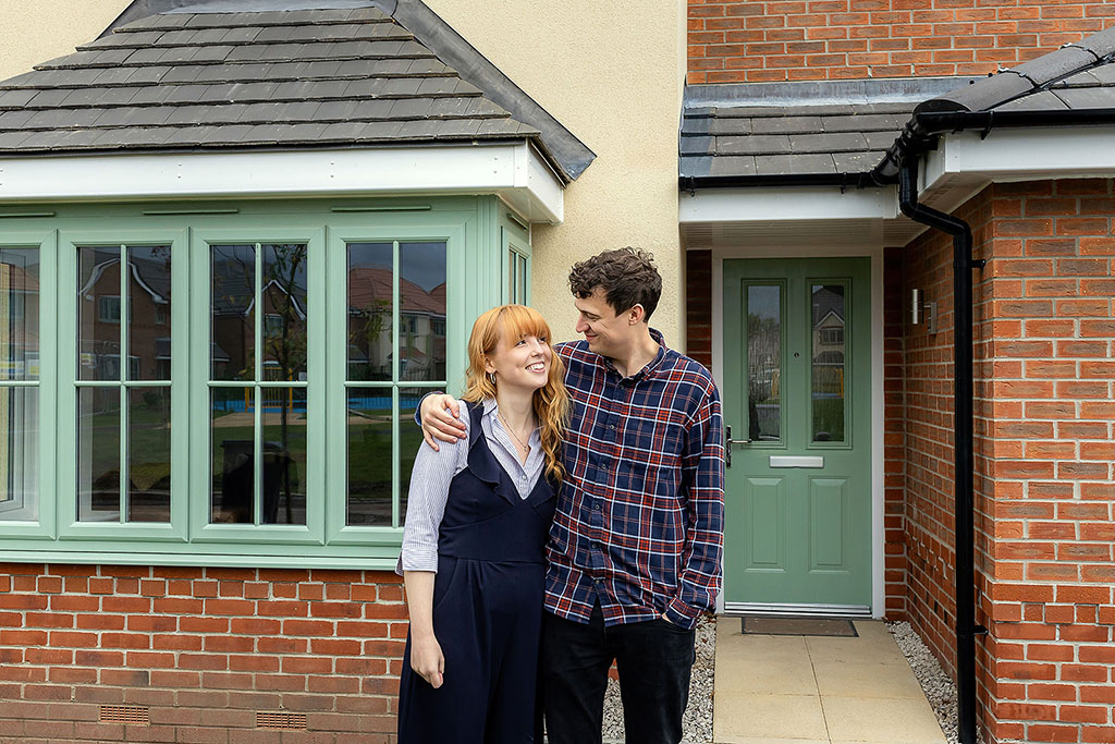 Couple stood infront of their new home.