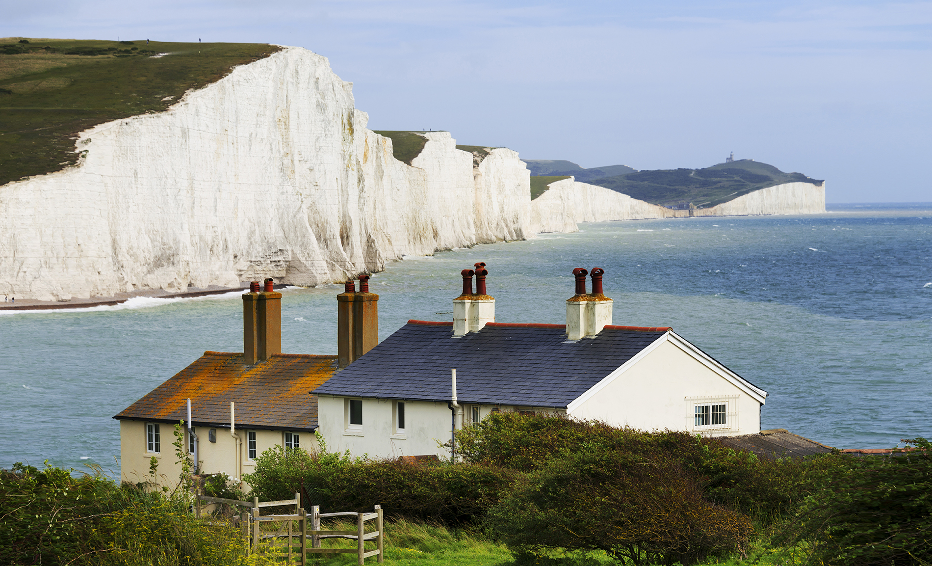 Houses on coast, with cliffs and sea in background.