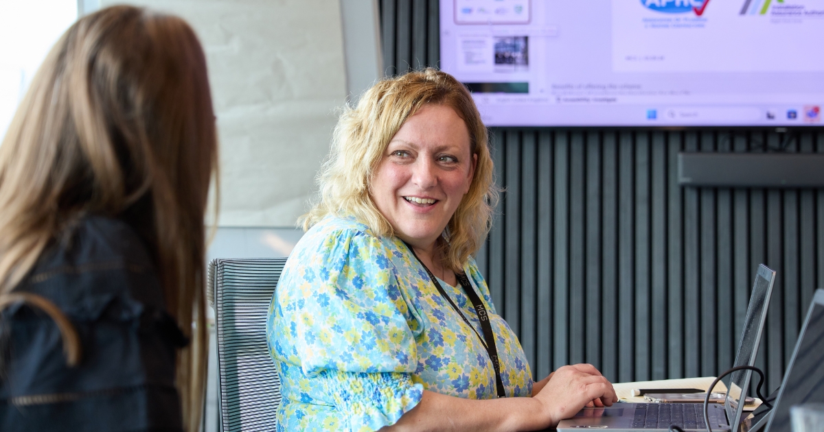 Woman sat in office laughing.