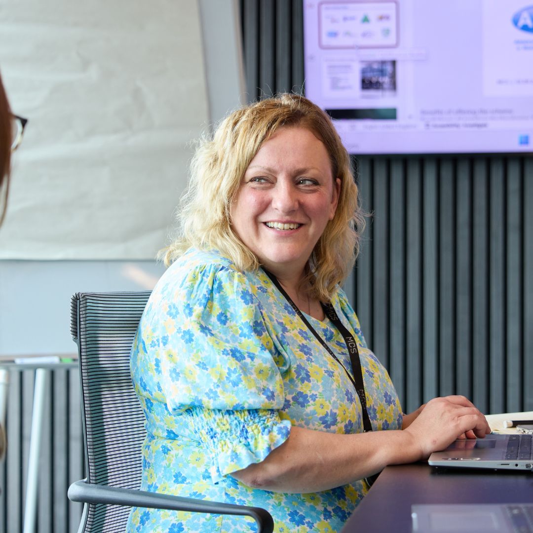 woman sat at table smiling.