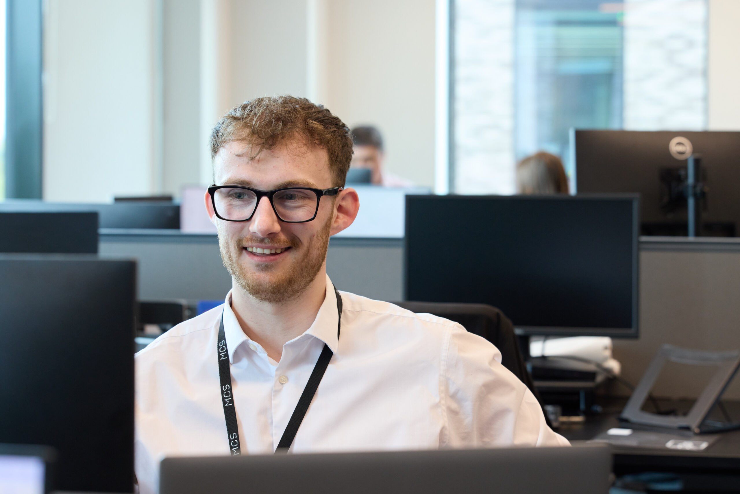 Man sat at desk smiling.