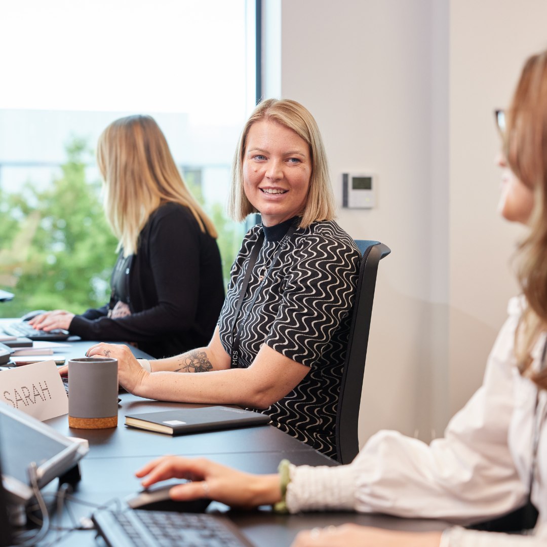 Three women sat at desk.