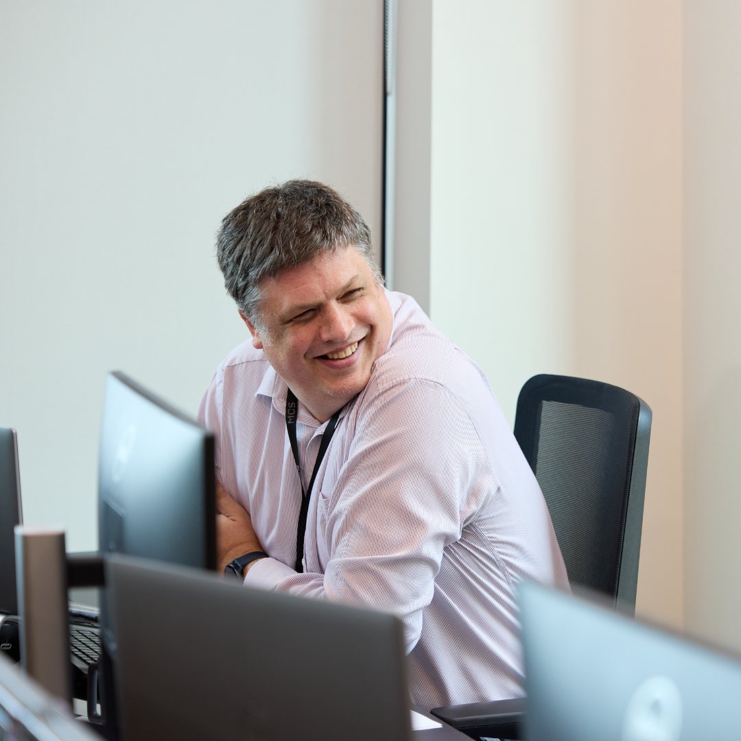 man sat at desk smiling