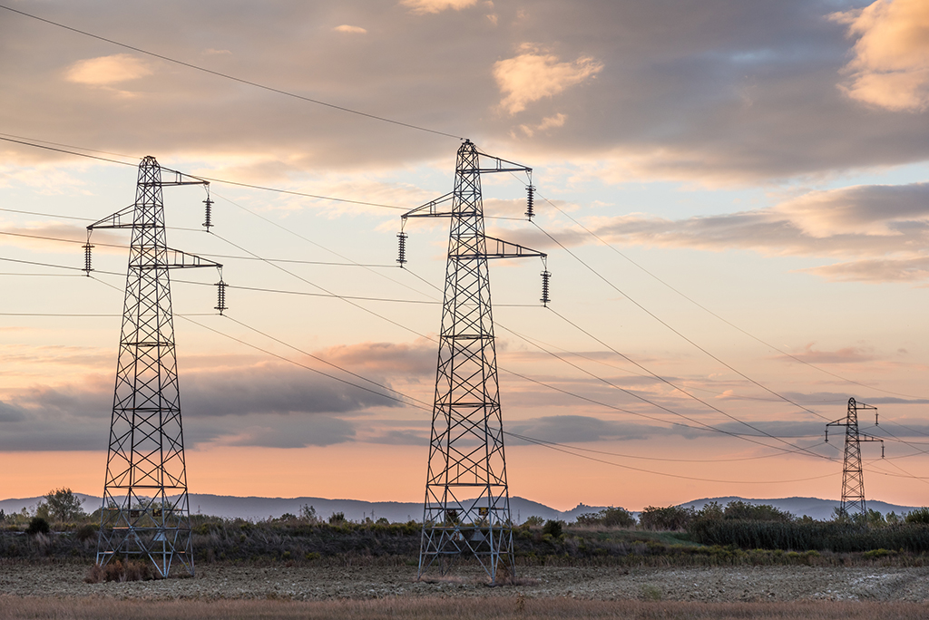 Sun setting behind a row or pylons.