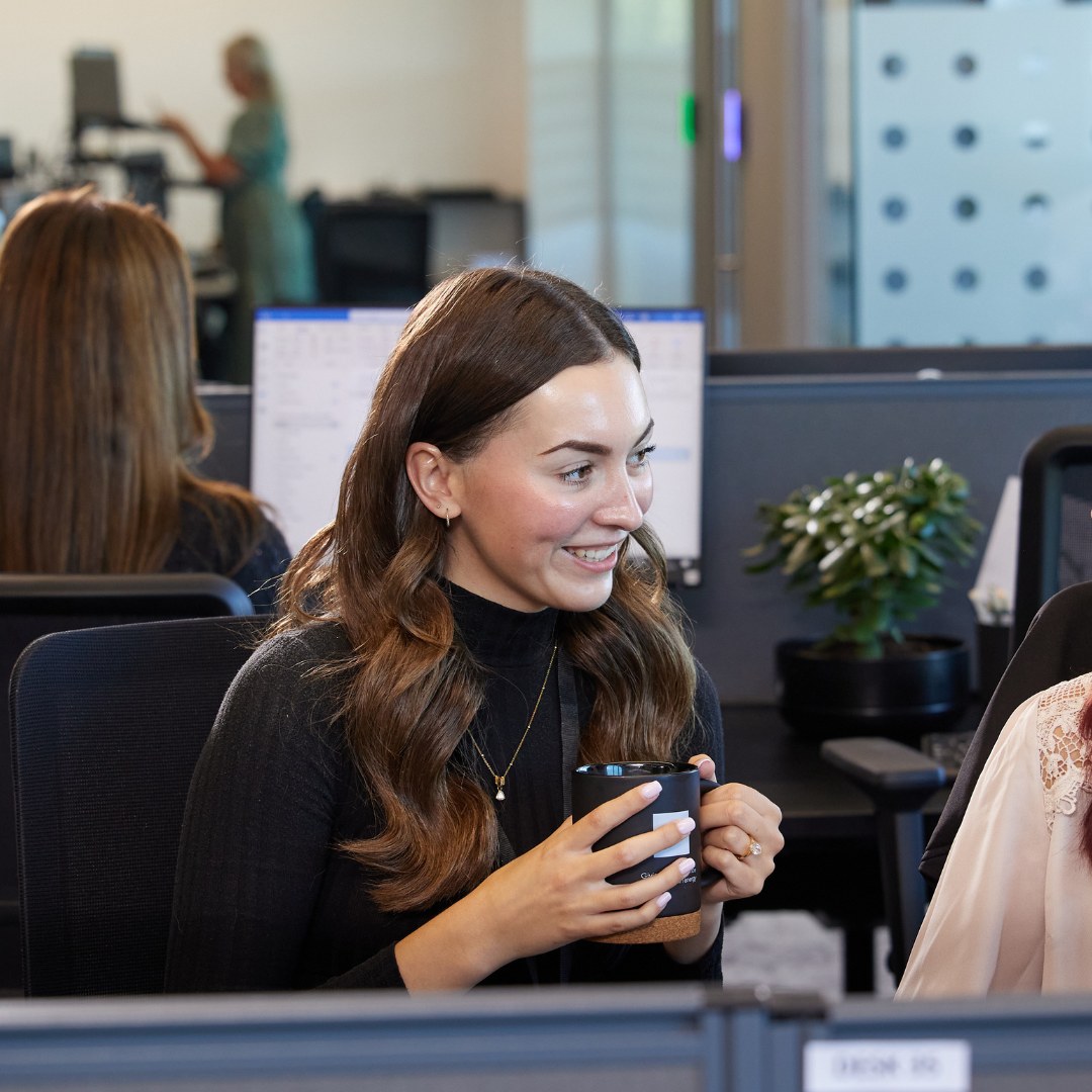 Woman holding mug at desk.