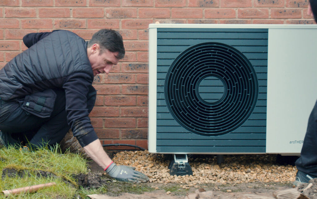 Installer crouched down next to heat pump.