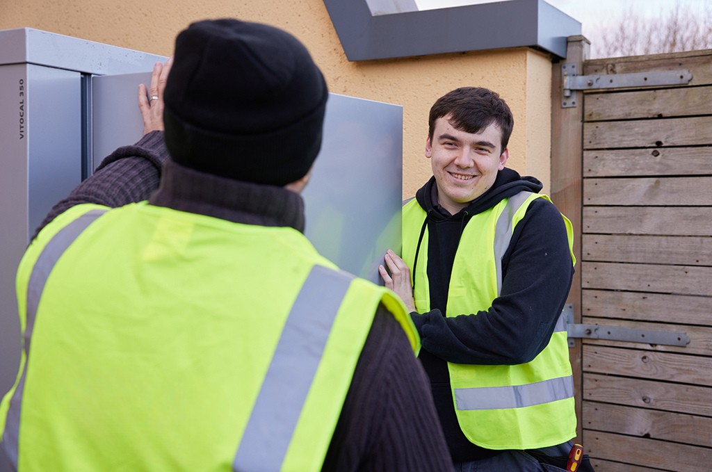 Installers carrying heat pump.
