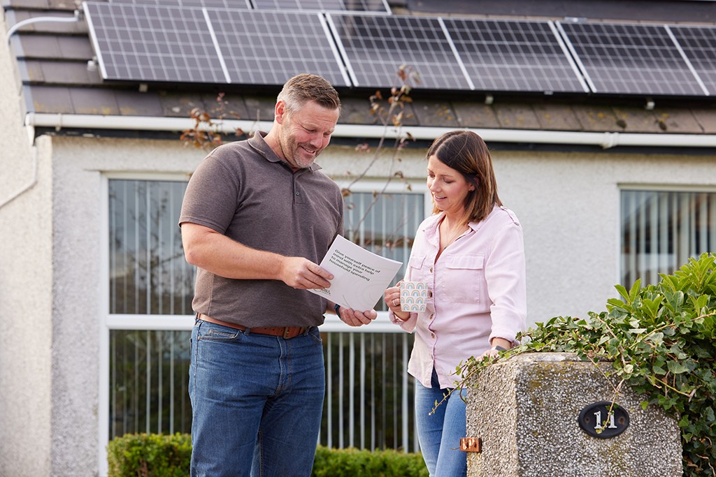 Homeowner and installer stood infront of house with solar panels.