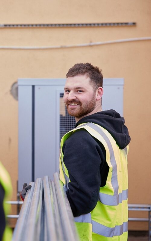 Installer in hi vis looking back smiling.